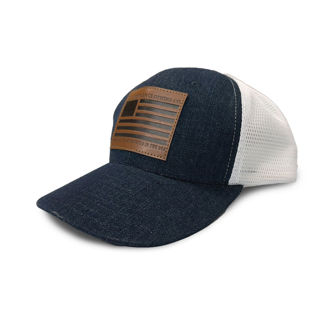 Blue denim cap with white mesh back and brown leather patch on a white background