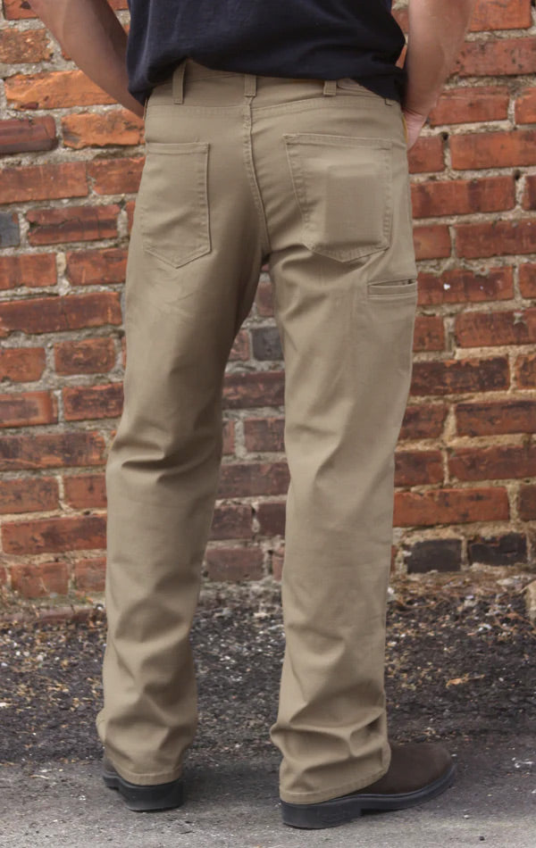 Person wearing beige pants standing against a brick wall.