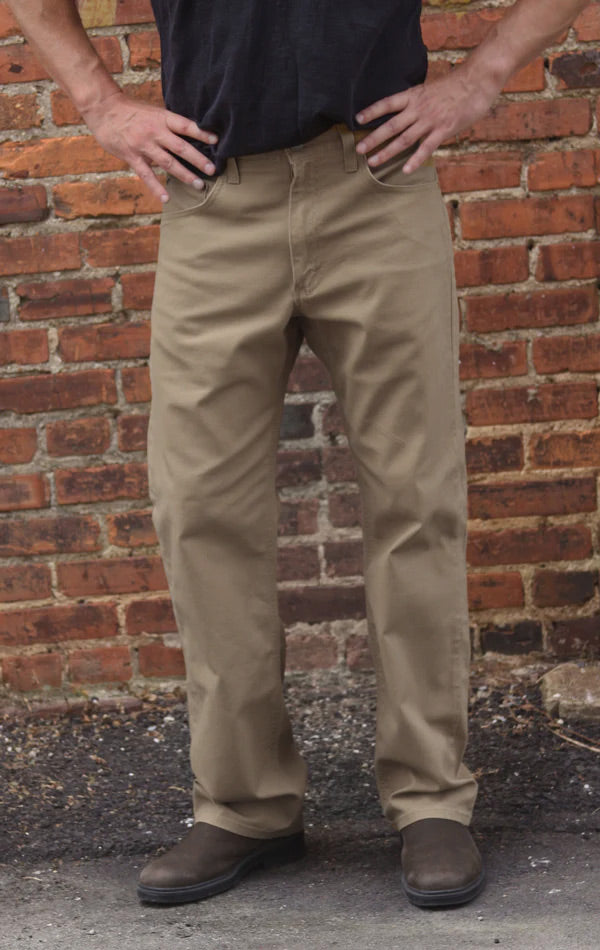 Person wearing beige pants standing against a brick wall.